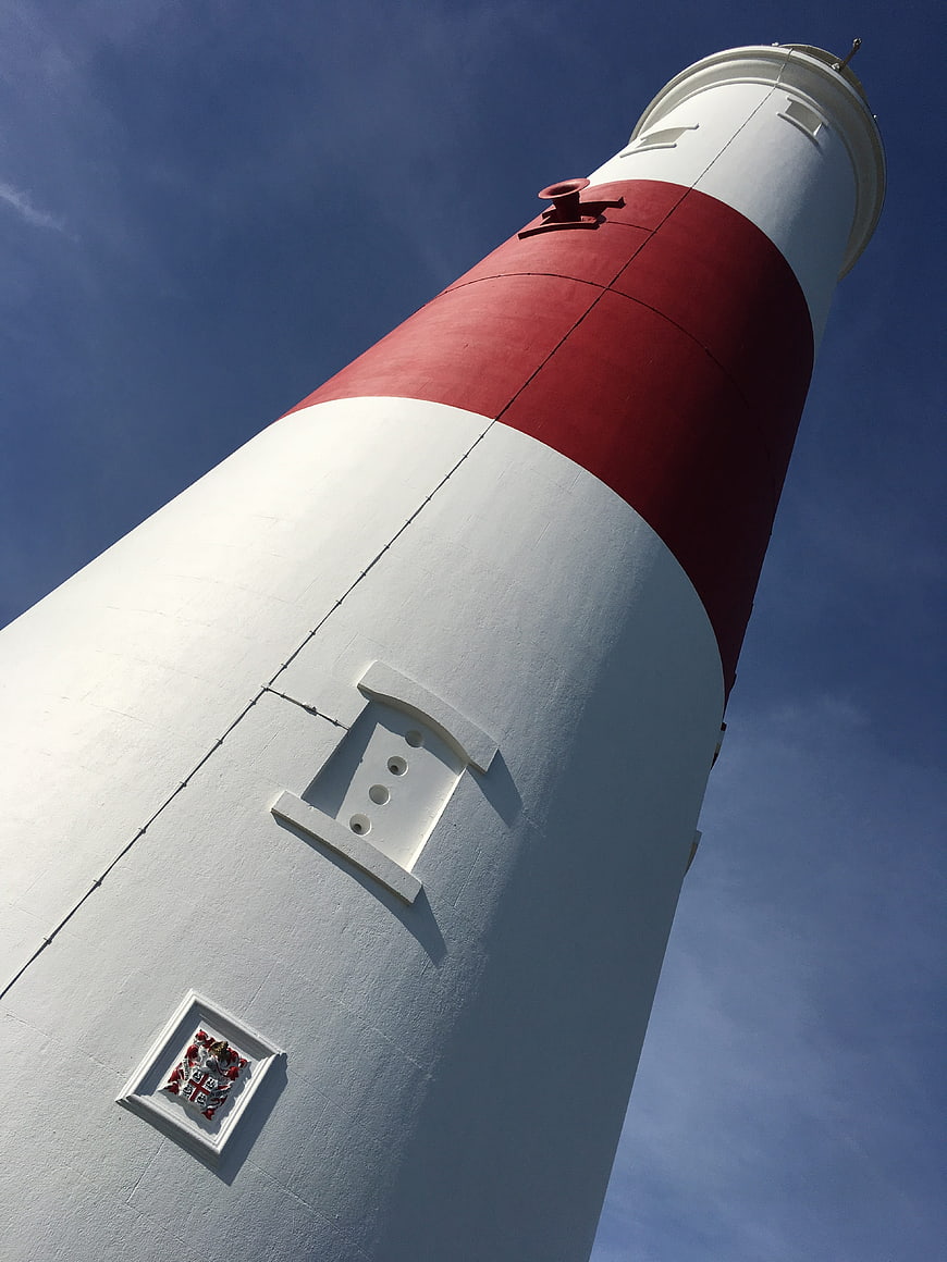 Low angle view of red and white striped lighthouse against blue sky