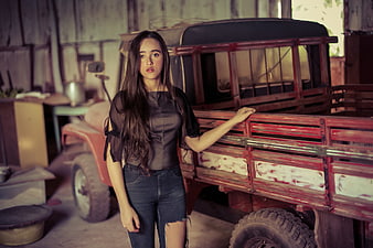 Young Woman Standing by Vintage Red Truck in Rustic Barn