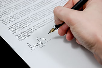 Hand signing a business document with a fountain pen