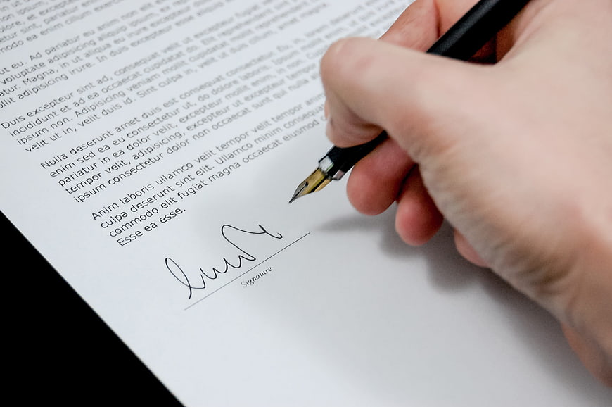 Hand signing a business document with a fountain pen