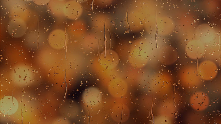 Raindrops on glass with warm golden bokeh lights at night