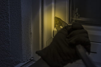 Gloved Hand Using Crowbar On Window Frame At Night