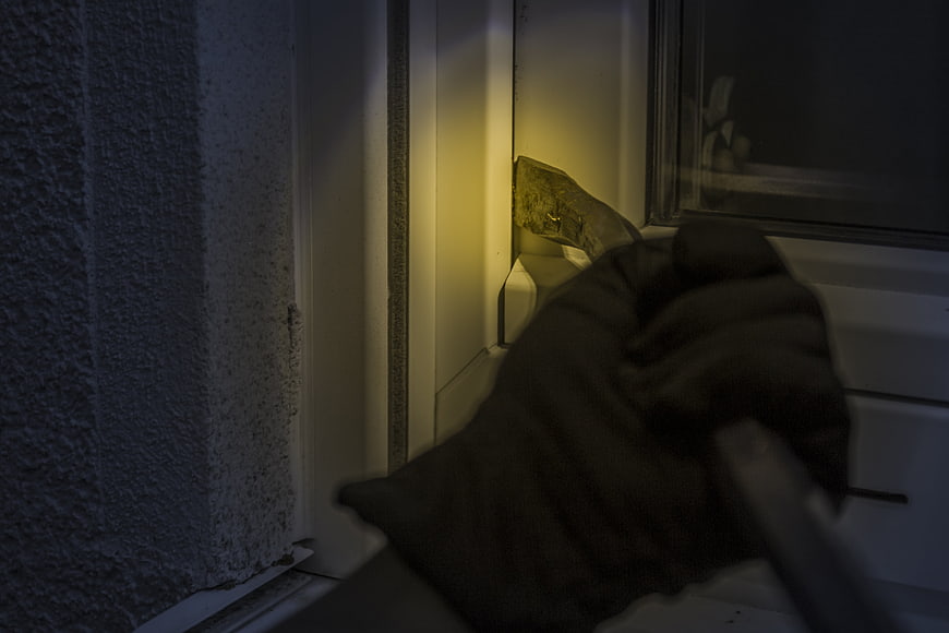 Gloved Hand Using Crowbar On Window Frame At Night