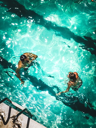 Aerial View of Couple Swimming in Turquoise Pool