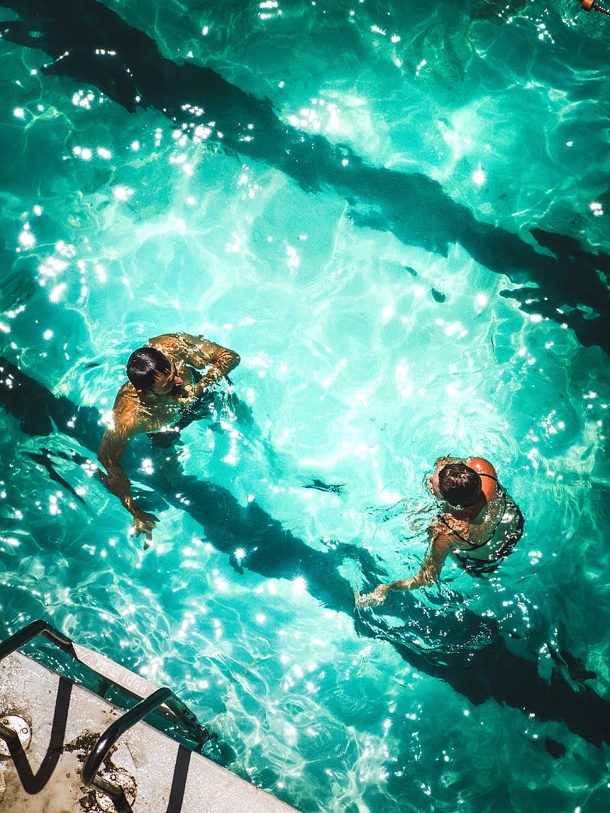 Aerial View of Couple Swimming in Turquoise Pool
