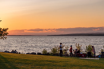 People relaxing by lake during golden sunset