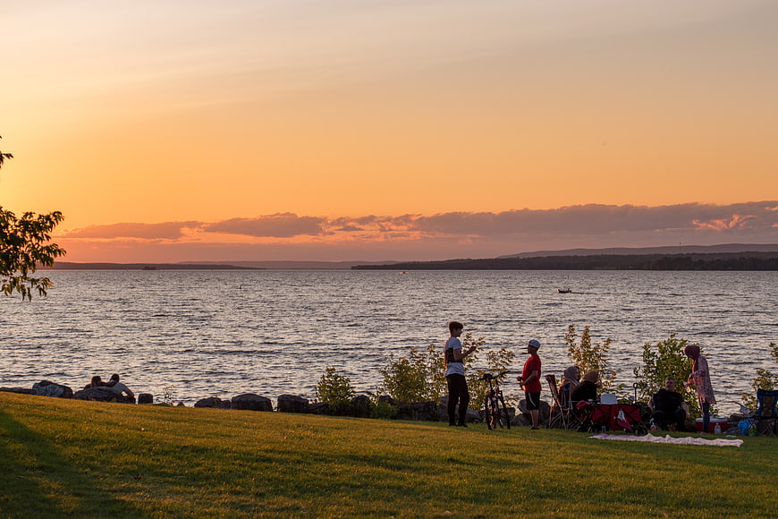 People relaxing by lake during golden sunset