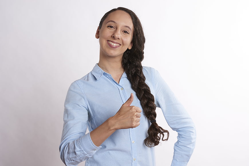Smiling woman with long braid giving thumbs up in blue shirt