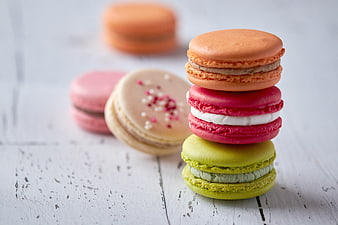 Stack of colorful macarons on white wooden background