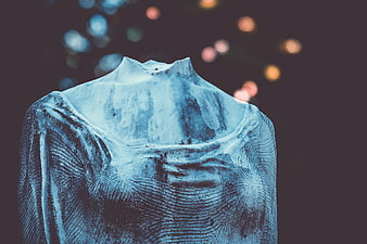 Close-up of weathered headless stone sculpture with bokeh background