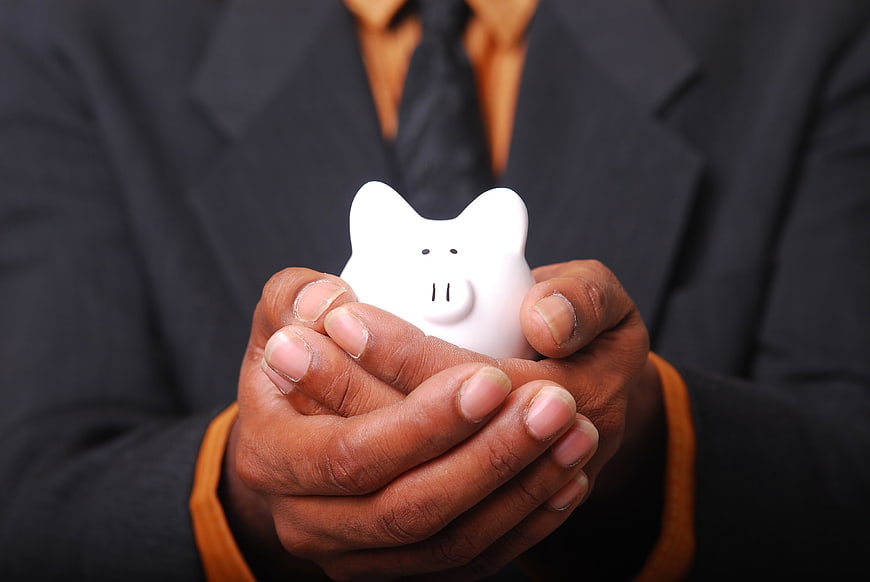 Businessman holding white piggy bank for savings concept