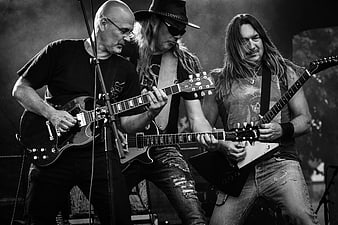Three Rock Musicians Playing Electric Guitars on Stage