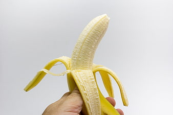 Hand Holding Half-Peeled Yellow Banana Against White Background