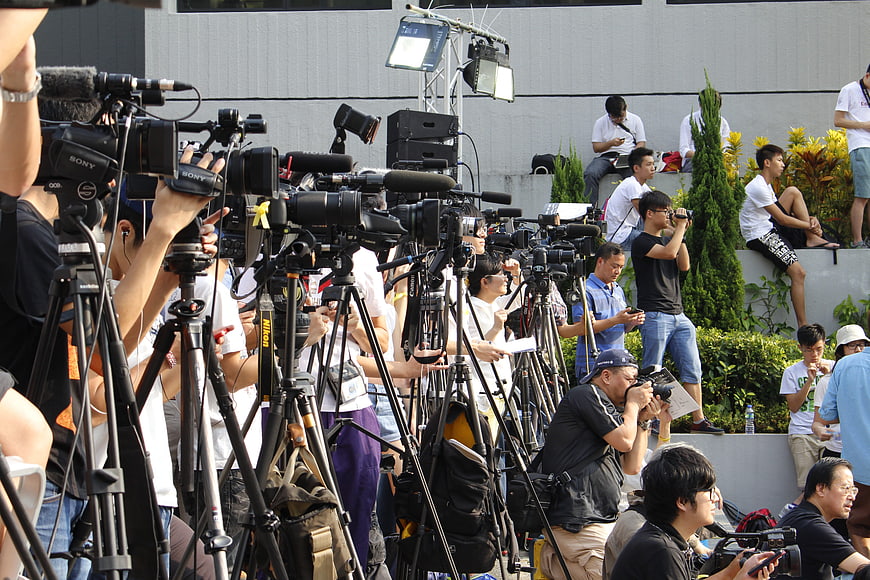 Crowd of journalists and cameras at outdoor press event