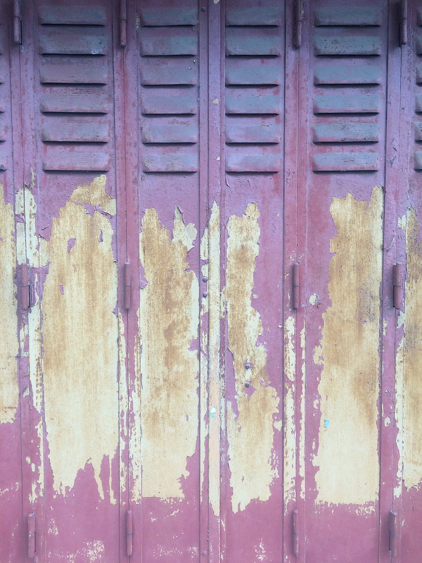 Weathered purple metal shutters with peeling paint texture