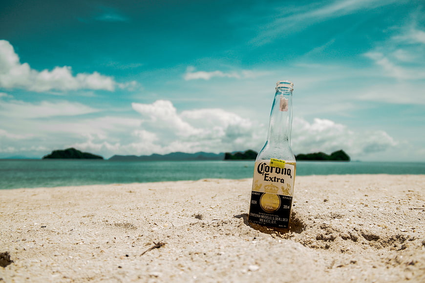 Corona Extra beer bottle standing in tropical beach sand