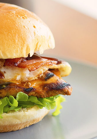 Close-up of a grilled chicken burger with bacon, cheese, and lettuce