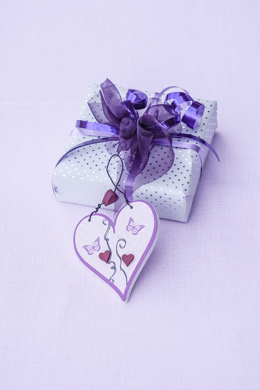 Purple Gift Box With Heart Ornament And Ribbon On White Background