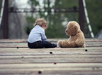 Toddler Boy Sitting with Teddy Bear on Wooden Deck