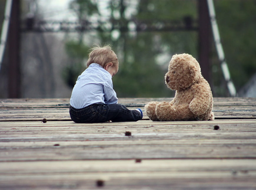 Toddler Boy Sitting with Teddy Bear on Wooden Deck