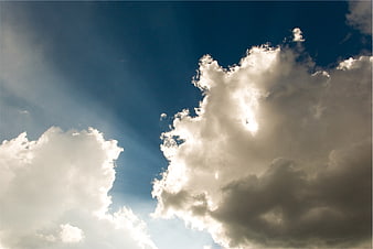 Dramatic Sun Rays Breaking Through Clouds in Blue Sky