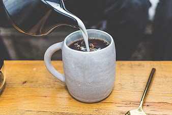 Pouring Milk into Coffee Mug on Wooden Table