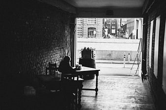 Silhouette of person sitting in dark room looking out window