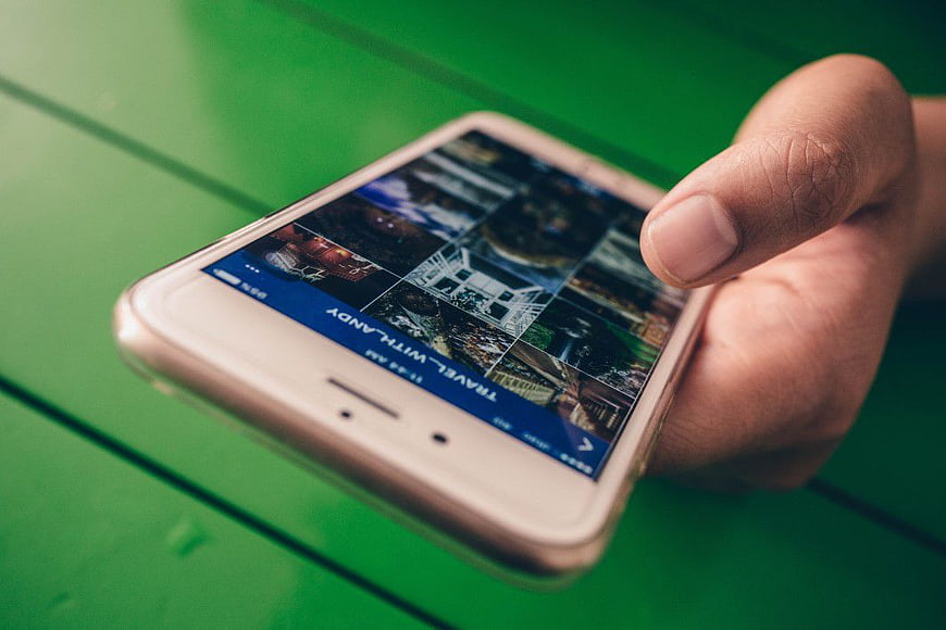 Hand holding smartphone displaying travel app on green background