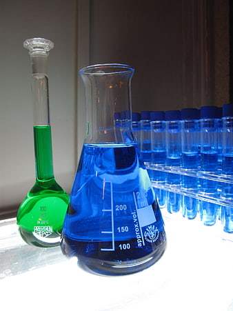 Laboratory glassware with blue and green chemical liquids