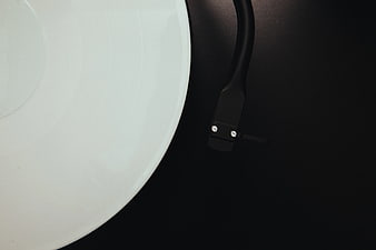 Close-up of white vinyl record and black turntable tonearm