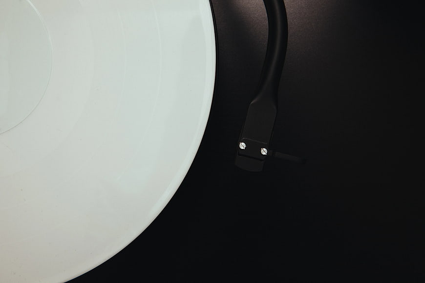 Close-up of white vinyl record and black turntable tonearm