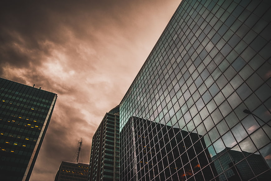 Low angle view of modern glass skyscrapers against dramatic sky