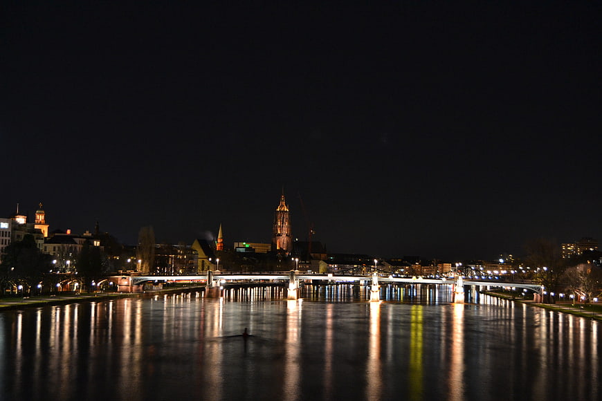 Night view of Frankfurt skyline with bridge and river reflections
