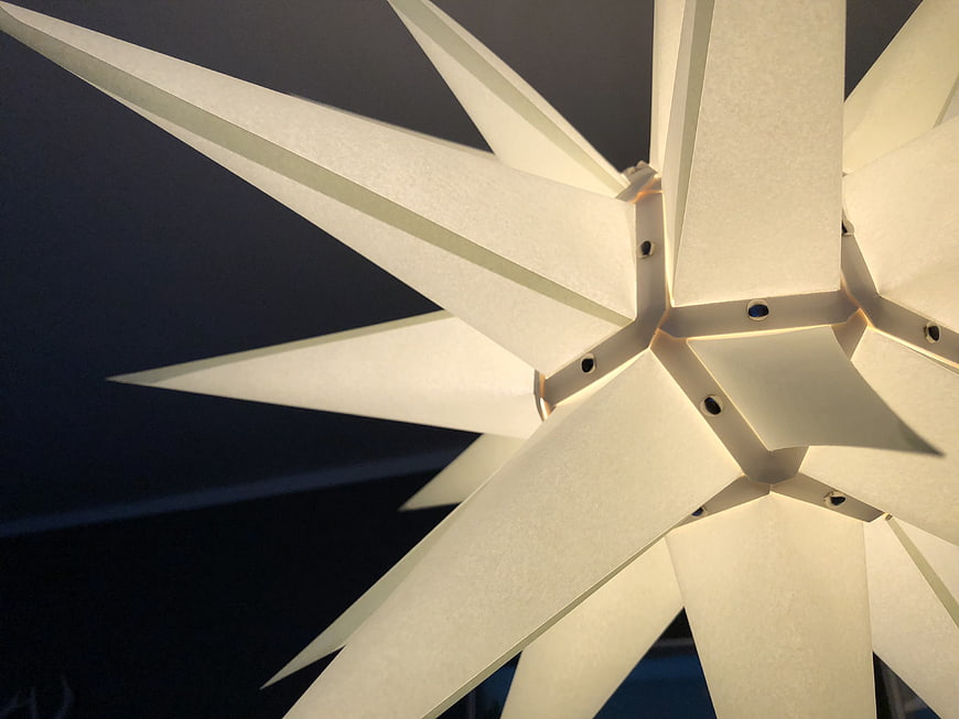 Close-up of white geometric star decoration against dark background
