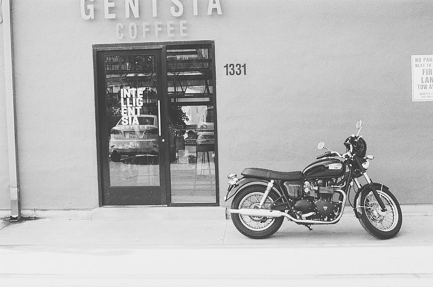 Black and white motorcycle parked outside coffee shop storefront