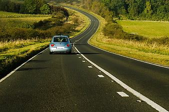 Silver Volkswagen Beetle driving on winding country road
