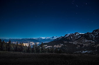 Starry Night Sky Over Snow-Capped Mountains and Lake