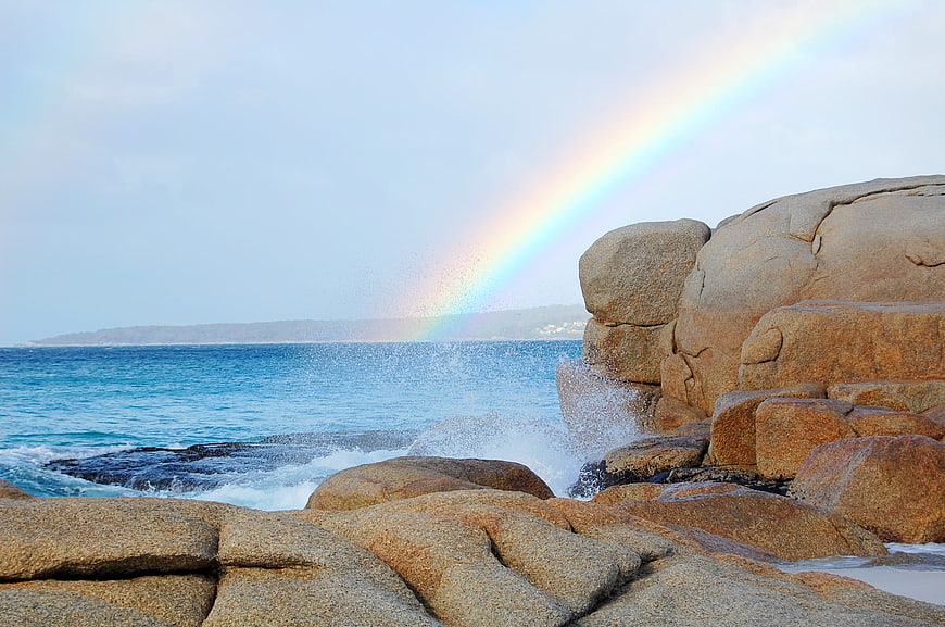Coastal Rainbow Over Rocky Shoreline And Blue Ocean