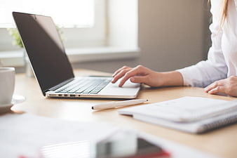 Woman typing on laptop in bright home office workspace