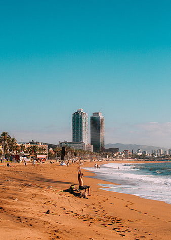 Man stretching on sandy beach with city skyline background