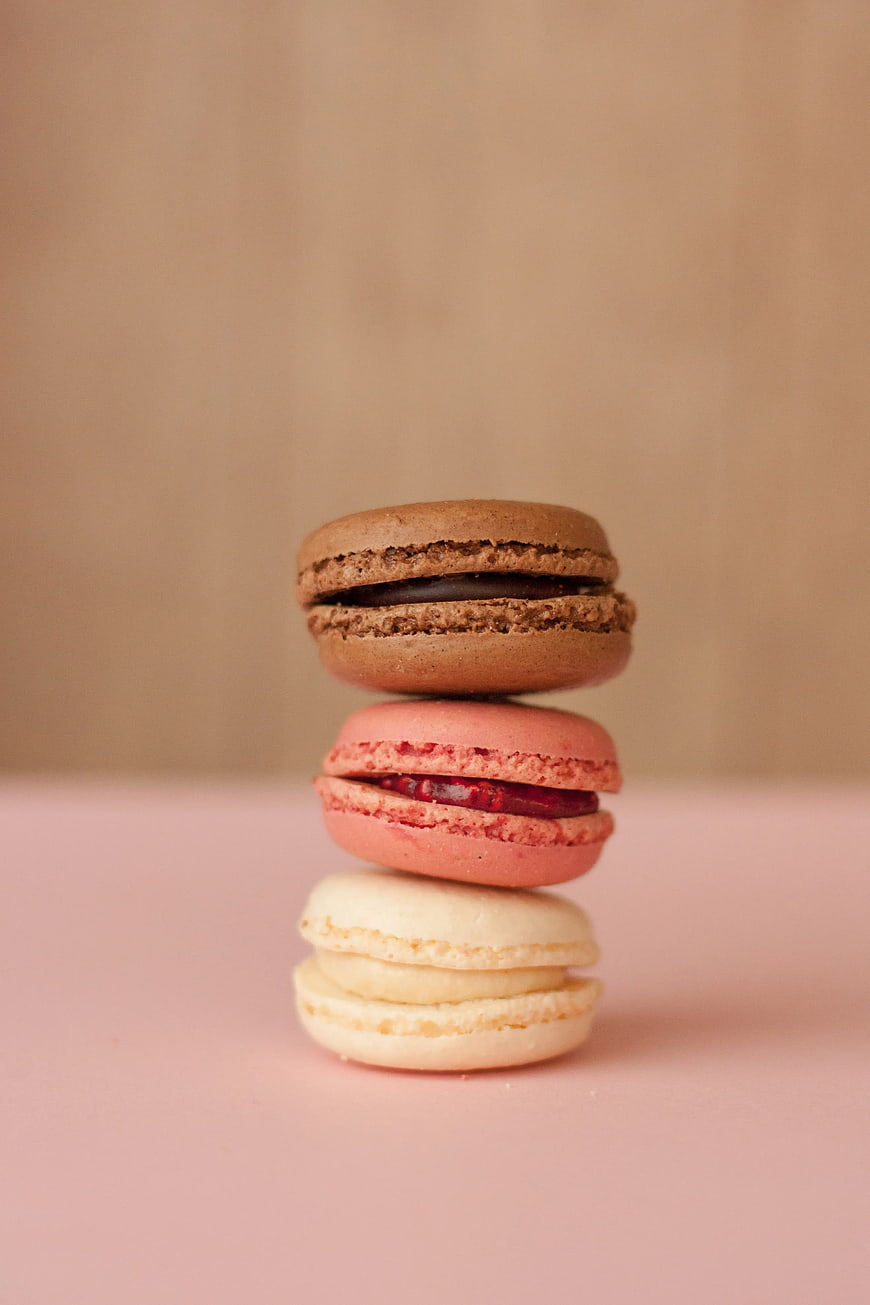 Stack of Three Colorful Macarons on Pink Background
