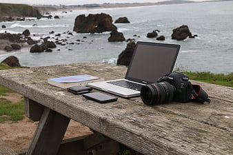 Laptop and Camera on Wooden Table by Ocean