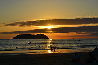Golden Sunset Over Beach with Silhouetted Island and People