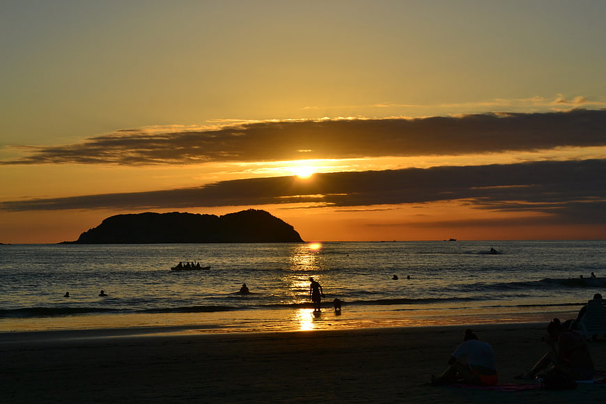 Golden Sunset Over Beach with Silhouetted Island and People