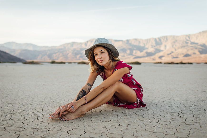 Woman in red dress sitting on cracked dry lake bed