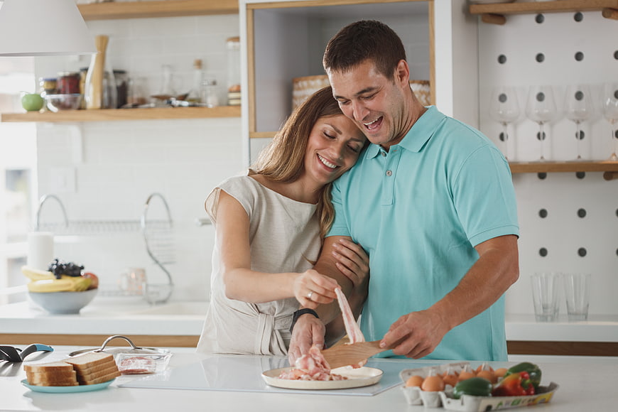 Happy couple cooking breakfast together in modern kitchen