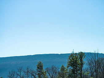 Blue Sky Over Forested Hills with Contrails
