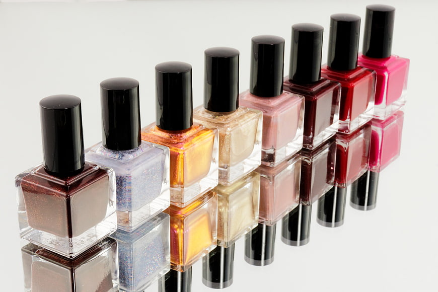Colorful nail polish bottles lined up on reflective surface