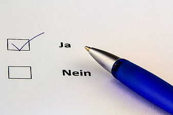 Blue pen checking yes box on German survey form
