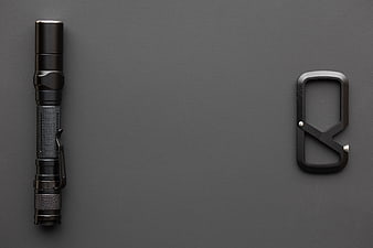 Black flashlight and carabiner on dark gray background